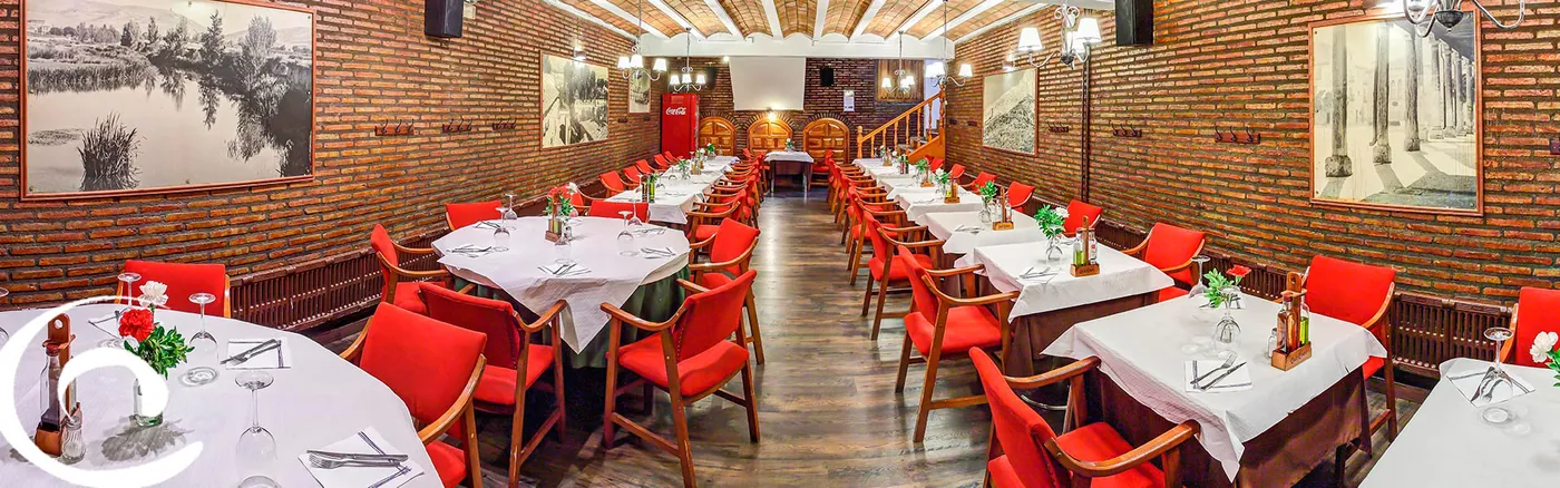 Comedor abovedado de ladrillo visto del Restaurante Capitol, con mesas vestidas y sillas rojas
