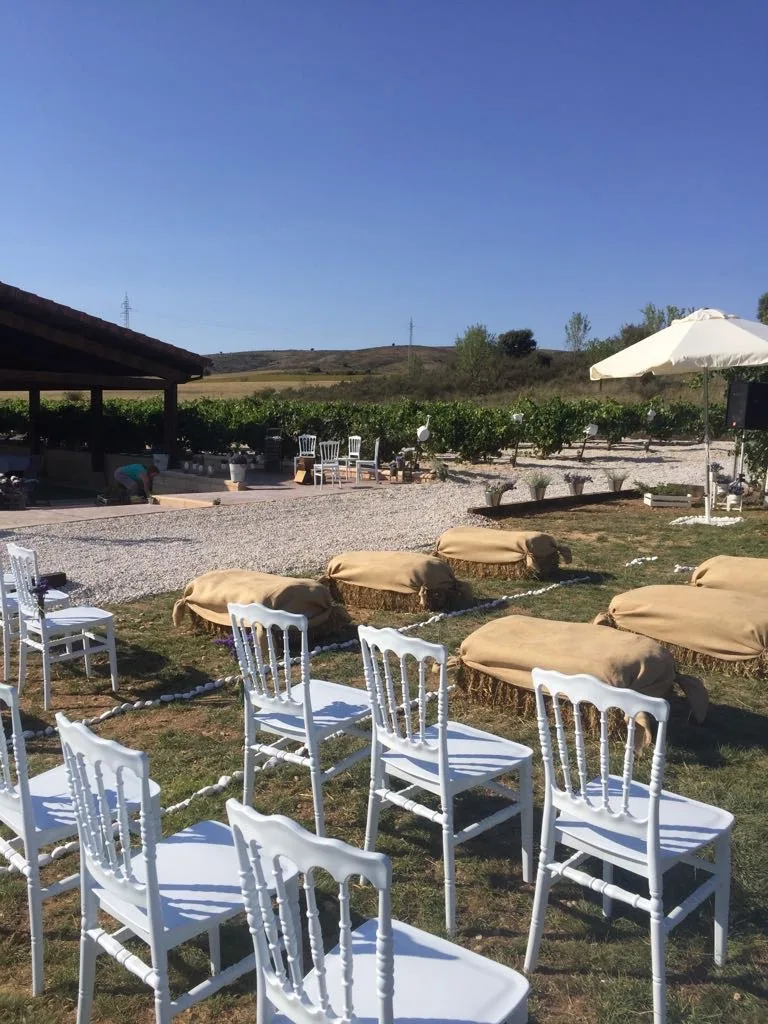 Sillas blancas alineadas para una ceremonia junto al porche