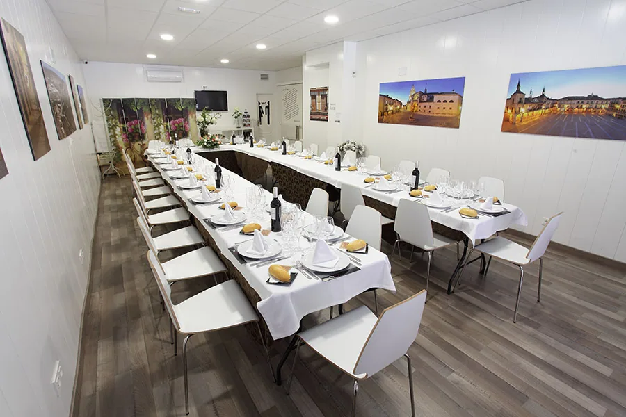 Salón luminoso con mesa larga vestida de blanco para una celebración