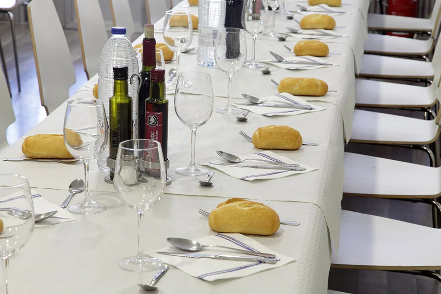 Mesa de banquete con panecillos, copas y cubertería preparada