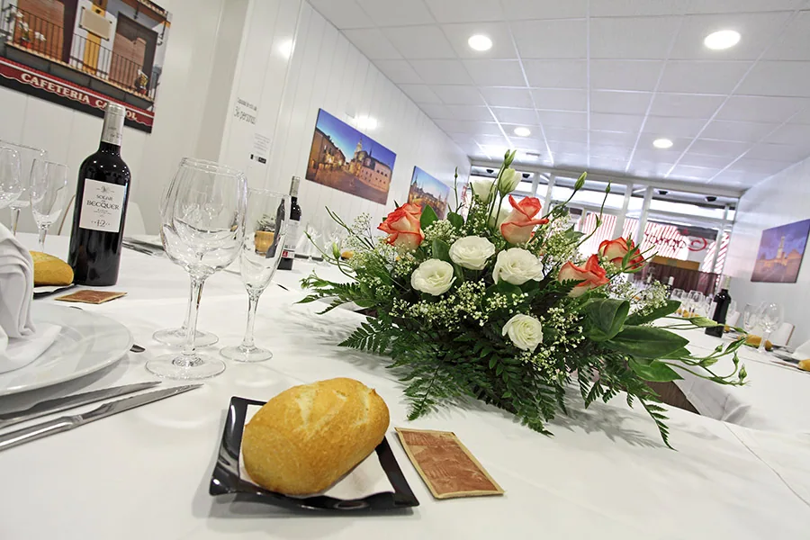 Mesa presidencial vestida con centro floral y copas para un banquete