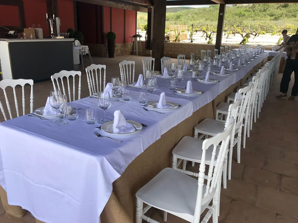 Banquete montado al aire libre con mesa larga vestida de blanco