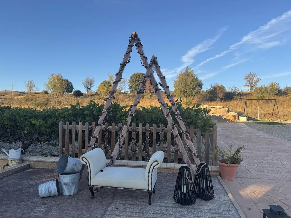 Rincón chill out de Los Arenales con sofá blanco bajo un arco de madera, junto al viñedo