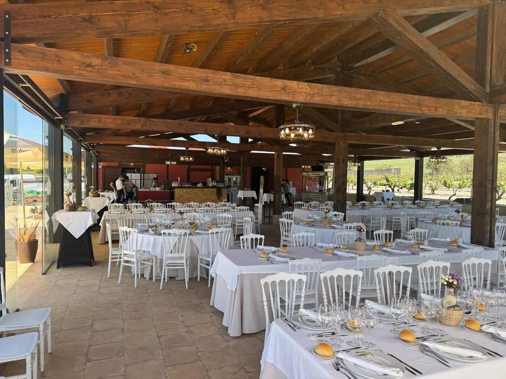 Mesas de banquete vestidas bajo el porche de madera de Los Arenales