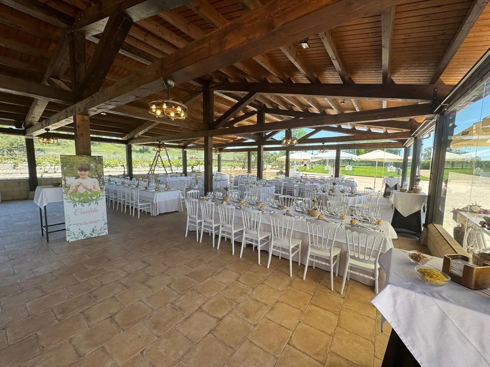 Banquete montado bajo el porche de madera de Los Arenales, con mesas largas vestidas de blanco